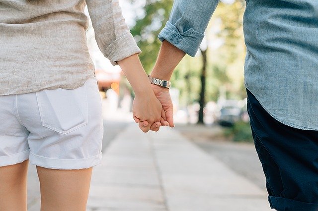 Muž a žena idú po ulici a držia sa za ruky 